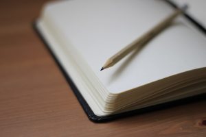 Close up of a book with a pencil on top that is on a desk